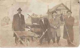 Men posing with wheelbarrow and shovels