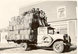 Three men on a truck stacked with hay