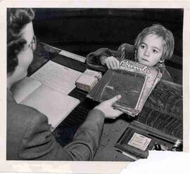 Librarian and young girl at circulation desk, Moose Jaw Public Library