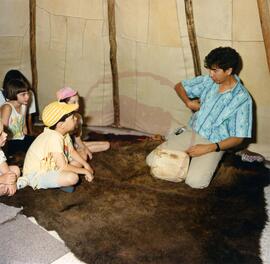 Storyteller Joseph Naytowhow with children in tipi