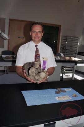 Dr. Ernest G. Walker in archaeology lab holding a pottery vessel found in Opimihaw creek