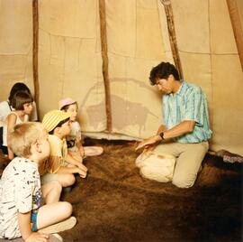 Storyteller Joseph Naytowhow with children in tipi