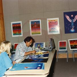 Artist Dennis Smokeyday demonstrating his painting technique for visitor