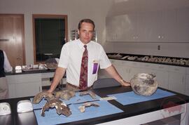 Dr. Ernest G. Walker in archaeology lab standing behind reconstructed pottery vessels