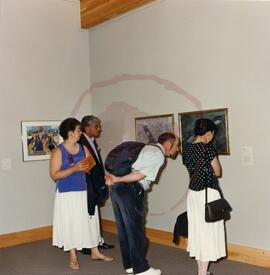 Visitors examining artworks in gallery