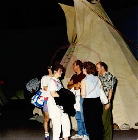 Five visitors in front of tipi in museum