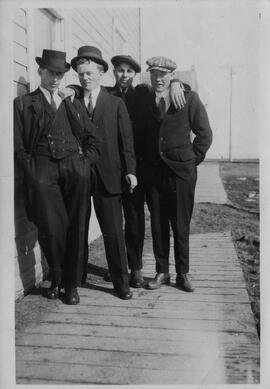 Four men in suits on a wooden sidewalk