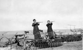 Two women with rifles among pioneer machinery