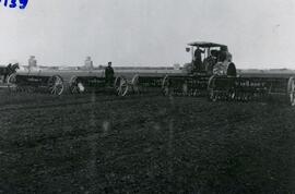 Five seeders being pulled by one tractor.