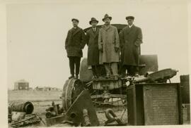 Four men in overcoats standing on a tractor