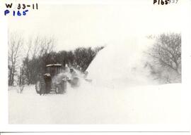 Snow blower clearing rural road.