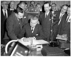 William Hamilton, Marc Drouin watch as John Diefenbaker signs a guest book in Montreal