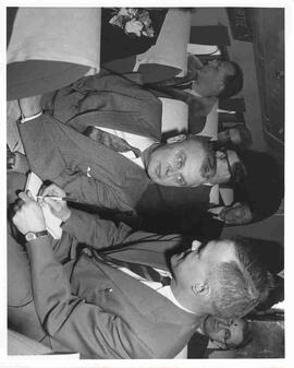 John Diefenbaker speaks with a reporter on an airplane