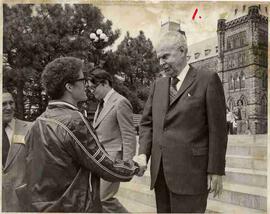 aJohn Diefenbaker standing on steps outside the Parliament Buildings