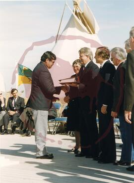 Person shaking hands with Prime Minister Brian Mulroney while he holds the TLE