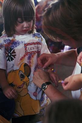 Person tying bracelet to child's wrist