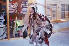 Dancer performing in traditional regalia through lobby of visitor centre