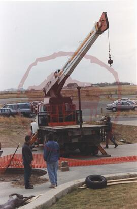 Three people examining boom truck crane